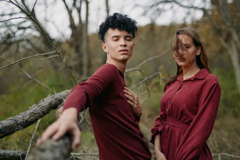 A candid portrait of a couple in matching burgundy outfits in a quiet woodland, conveying natural connection and emotional honesty, emphasizing ????????????? and ????????????? in their expressions.