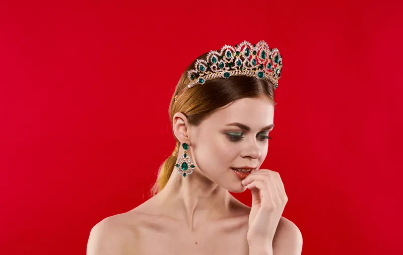 Портрет уверенной женщины на красном фоне с короной на голове