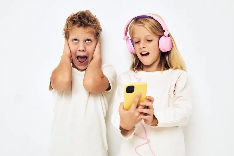 Молодой весёлый ребёнок улыбается с телефоном в руке