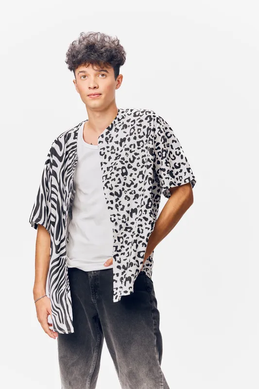 young man wearing stylish black and white animal print shirt with a white t-shirt, casual fashion, modern hairstyle, confident pose on light background