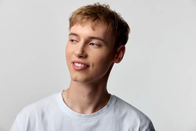 Young man in a white tee looks away in a clean studio, relaxed mood and soft lighting, casual fashion for lifestyle, product or branding projects