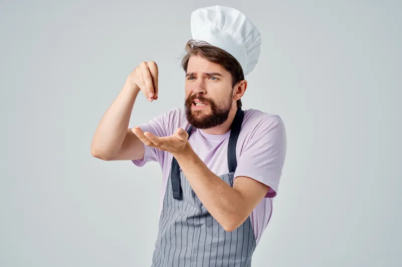 Мужчина в одежде шеф-повара на кухне занимается обработкой продуктов в пищевой индустрии