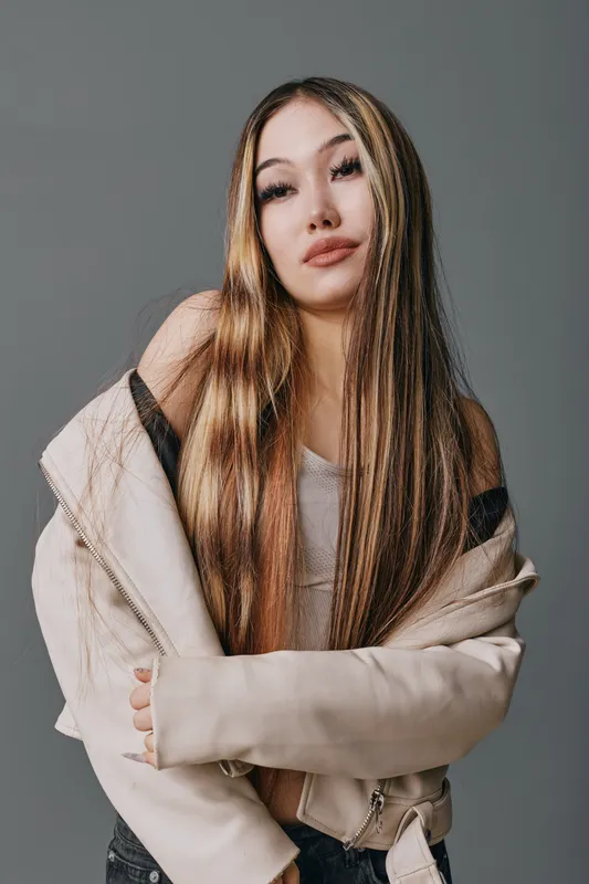 Young woman with long straight hair wearing light jacket posing against gray background confident stylish beauty portrait fashion model casual look.