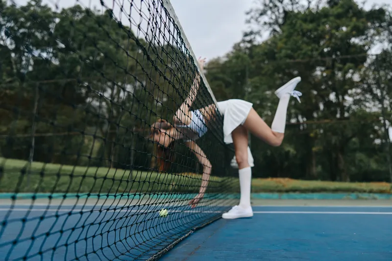 Energetic young female tennis player in sportswear displaying dynamic motion on a tennis court, embodying athleticism, joy, and dedication to sports