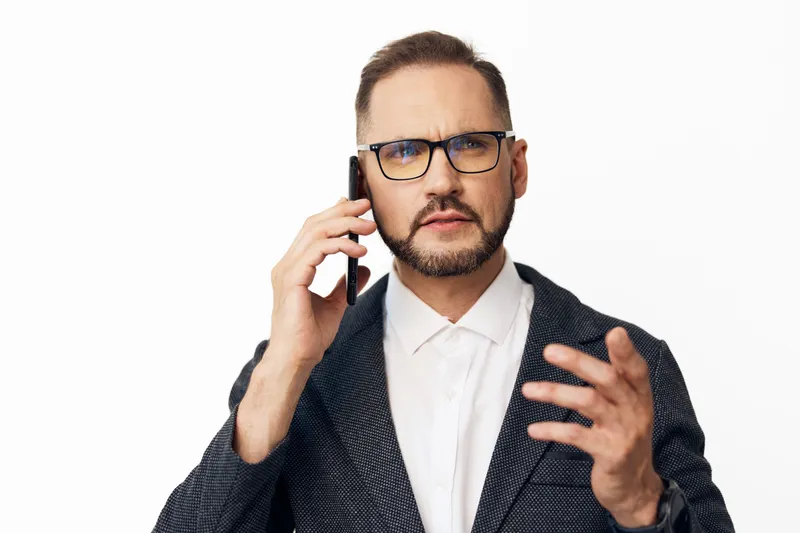 A focused business professional man on a phone call, expressing intent and confidence against a clean isolated white background, showcasing thoughtful emotion and steady leadership.