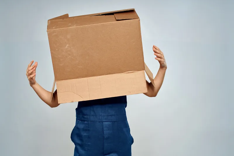 Женщина в рабочей форме занимается упаковкой коробок