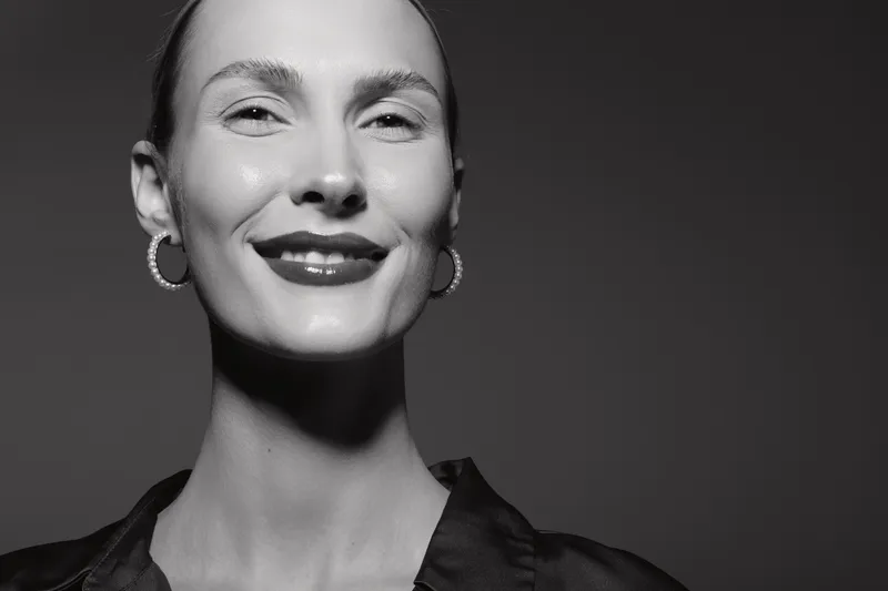 Portrait of a smiling white woman with pale skin and hoop earrings in studio lighting. Concept of happiness and confidence.