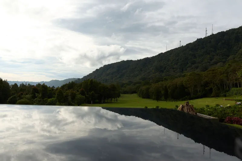 Tranquil landscape view reflecting mountains, greenery, and sky, perfect for relaxation and nature photography