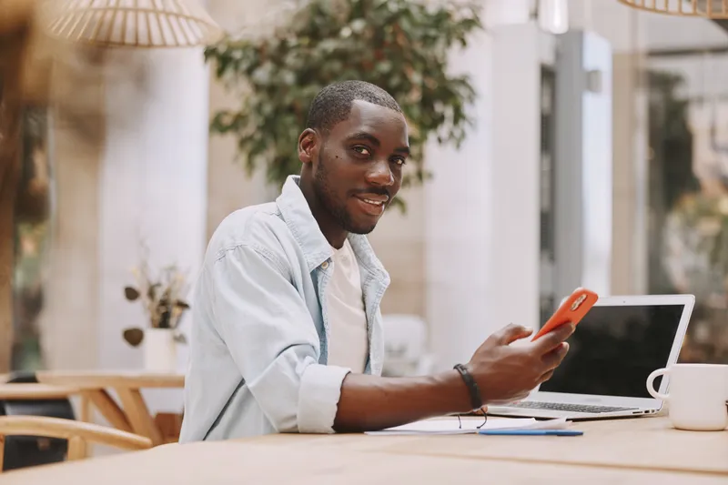 Взрослый мужчина-афроамериканец сидит за рабочим местом и работает за компьютером