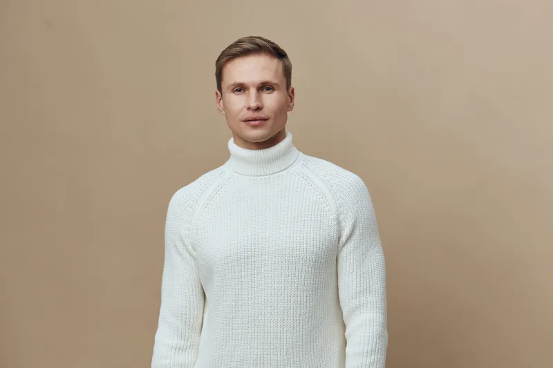 young caucasian man wear white knitted sweater look camera neutral face isolated on beige background digital detox concept