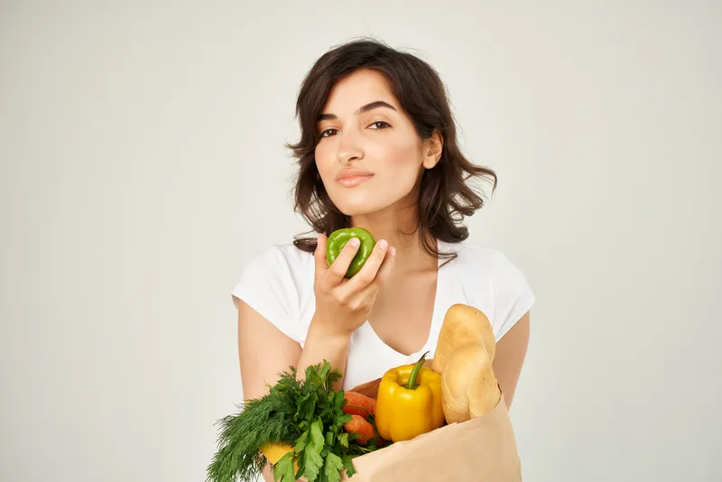 Весёлая брюнетка с пакетом продуктов, доставка из супермаркета