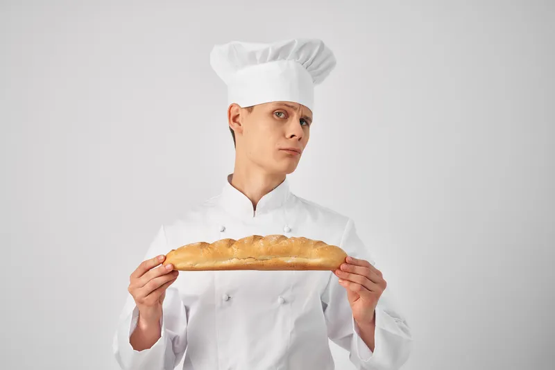 Мужчина в форме шеф-повара с батоном в руках, свежая еда, работа, светлый фон
