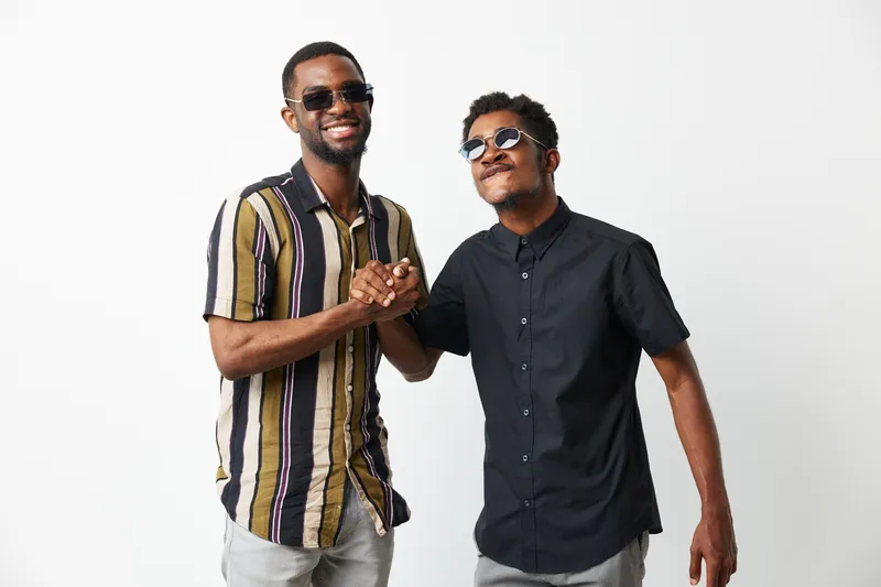 Two smiling black men dressed casually, exuding friendship and joy, perfect for capturing moments of camaraderie and connection in everyday life.