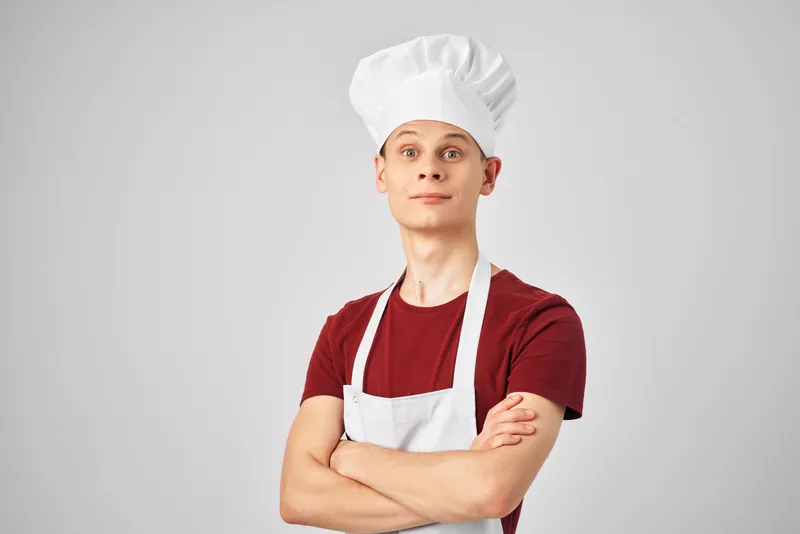 Мужчина в фартуке на кухне на светлом фоне, профессиональный повар