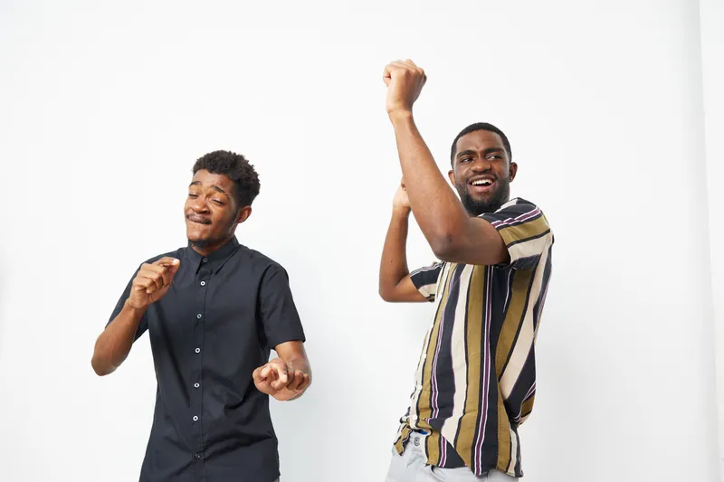 Joyful African American men dancing together, celebrating life with genuine smiles and vibrant energy. Perfect for conveying fun and camaraderie in photography.