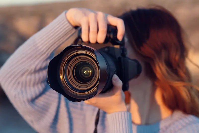 Красивая женщина-фотограф на природе в горах фотографирует модель на фоне пейзажа
