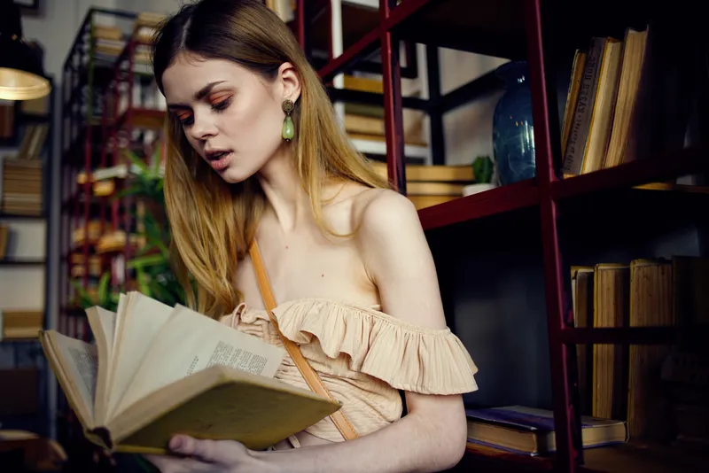 Женщина читает книгу в ресторане во время отпуска, занимаясь самообразованием