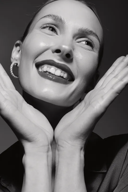 Close-up portrait of a smiling Caucasian woman with fair skin and bright eyes in black and white. Concept of joy and beauty.