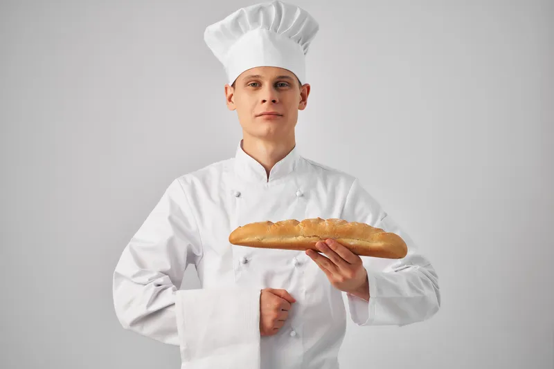 Мужчина в униформе повара, пекарь с буханкой хлеба в руках, свежий продукт
