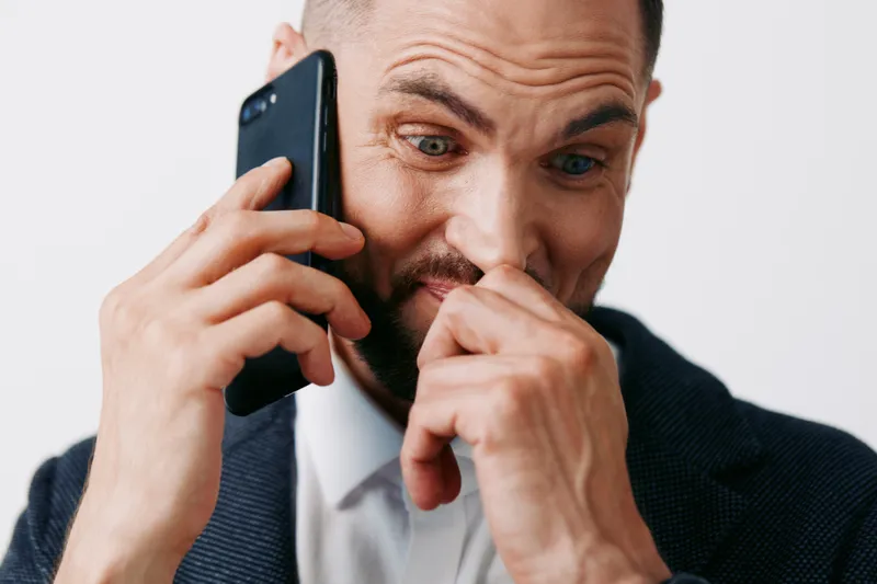A professional man on a phone, captured mid conversation with a focused yet anxious expression. Isolated colored background highlights a corporate mood and business presence.