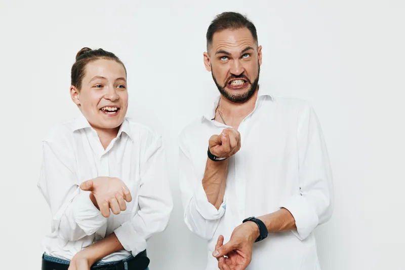 A male business professional stands against an isolated colored background, showing emotion as he points and smiles. This confident, energetic moment conveys motivation and leadership for corporate,