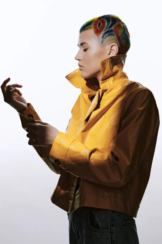 woman with colorful hairstyle wearing a yellow jacket, artistic haircut, stylish clothing, isolated white background, modern fashion portrait