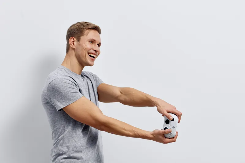 Happy young caucasian man holding game controller smiling gaming at home digital detox casual clothes studio portrait concept