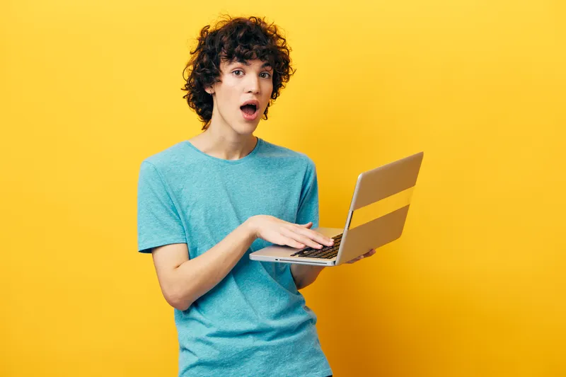 Кудрявый парень работает с ноутбуком онлайн, финансы, образ жизни, технологии