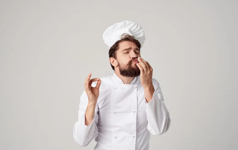 Бородатый мужчина-шеф-повар занимается кулинарией в профессиональной индустрии, демонстрируя эмоции