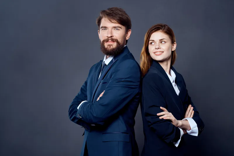 Весёлые мужчина и женщина, коллеги по работе, в команде на тёмном фоне