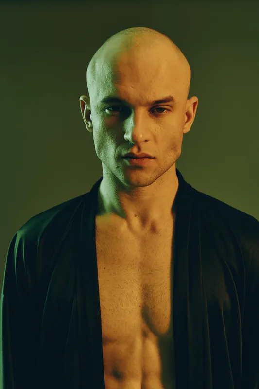 Portrait of a serious man in a black robe, featuring dramatic lighting that highlights his facial features and emphasizes the mood. Black and white style.