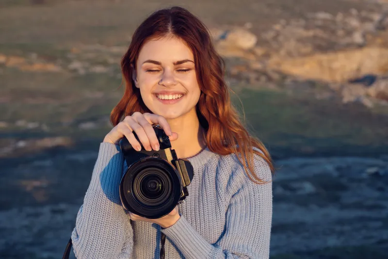 Жизнерадостная женщина-фотограф с камерой на фоне природы, пейзаж, образ жизни