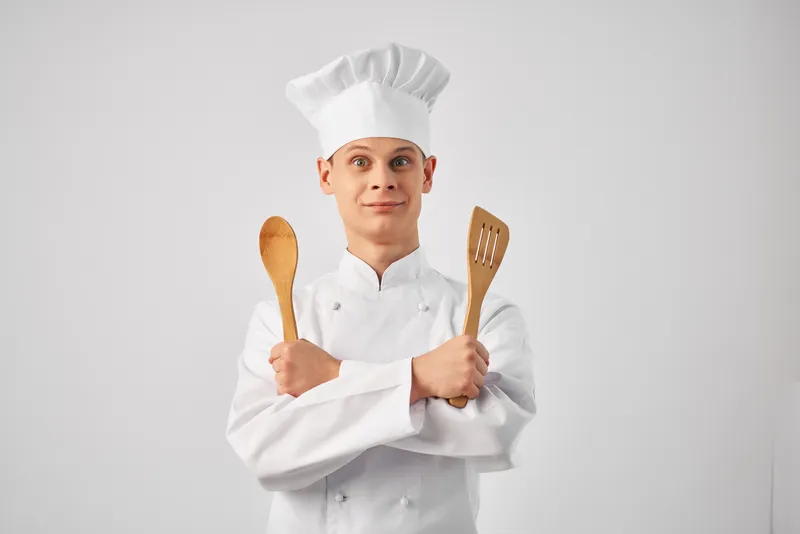 Шеф-повар с кухонной утварью профессионально работает на кухне ресторана