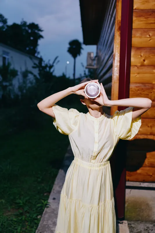 person woman dress drinking jar outdoor evening wooden candid, in yellow dress at wooden house, authenticity inclusivity