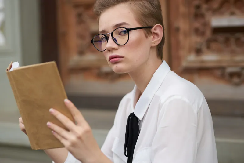 Образованная женщина в очках, студентка возле института, с книгой в руках, модель, крупный план