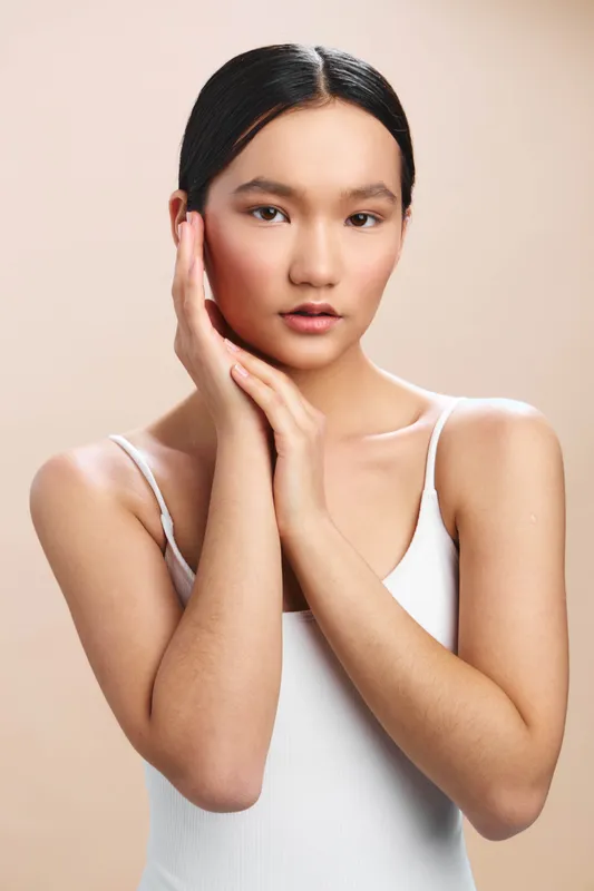 asian woman posing gracefully in a clean studio setting. soft lighting highlights her features, creating a calm and elegant portrait ideal for beauty, fashion, and lifestyle projects.