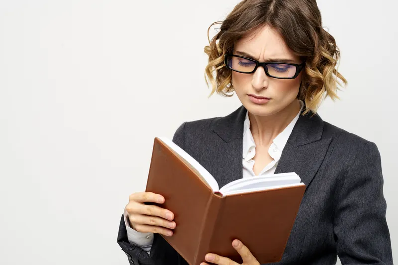 Деловая женщина с блокнотом и очками работает на светлом фоне