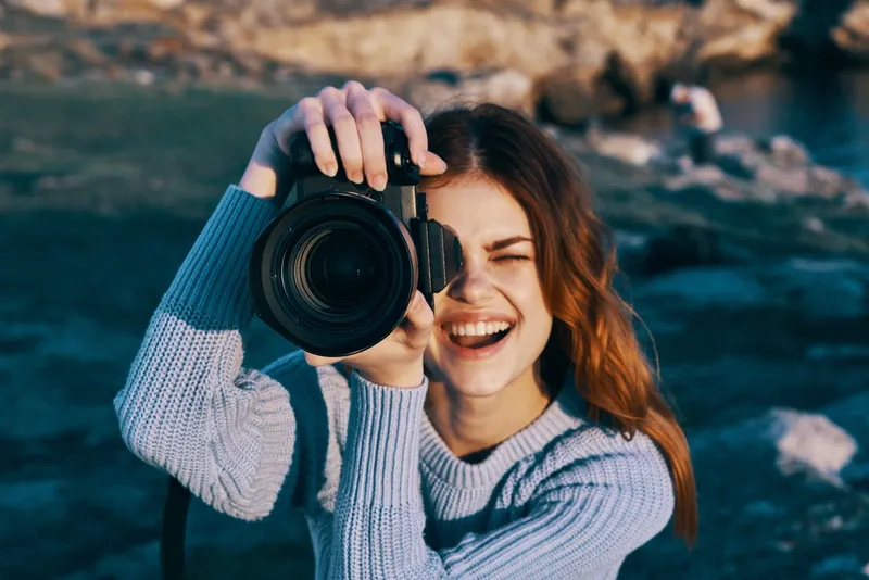 Жизнерадостная женщина-фотограф на открытом воздухе, скалистые горы, профессиональная работа, туризм