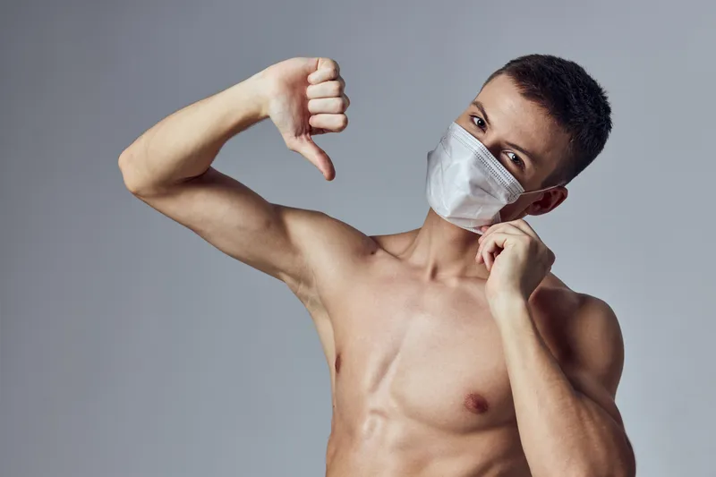 Спортивный мужчина показывает большой палец вниз, медицинская маска, здоровье, тренировка