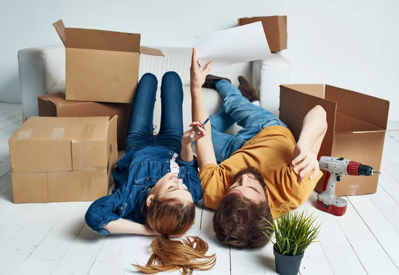 Мужчина и женщина лежат на полу рядом с коробками, делая ремонт в комнате и переезжая