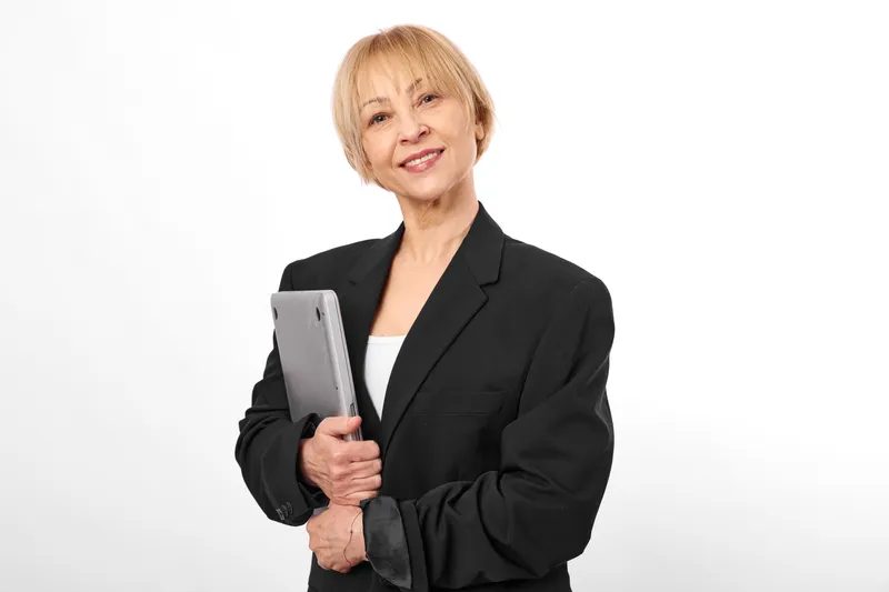 Senior businesswoman smiling, holding tablet, presenting technology in a corporate portrait on a clean white background, professional communication, modern work