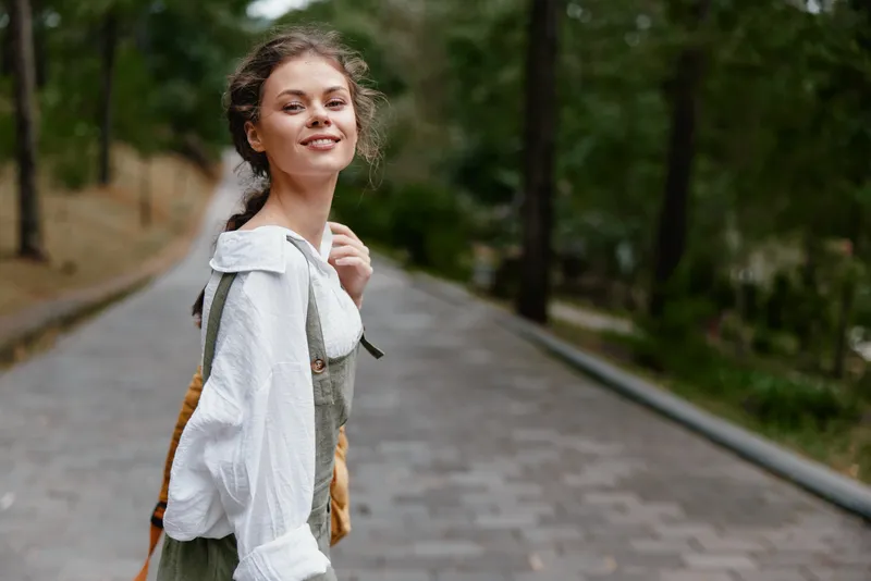 Young woman in casual outfit smiling in a green park, capturing a joyful moment, perfect for lifestyle imagery, showcasing happiness and nature