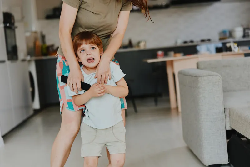 Caring woman comforting a distressed child in a cozy home environment, showcasing a warm and nurturing atmosphere in family life.