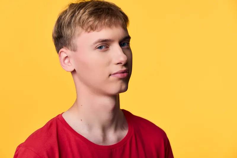Young man in a red shirt against a bright yellow backdrop, studio lighting highlights clean features, casual style and confident mood ideal for lifestyle and stock photography, perfect for modern