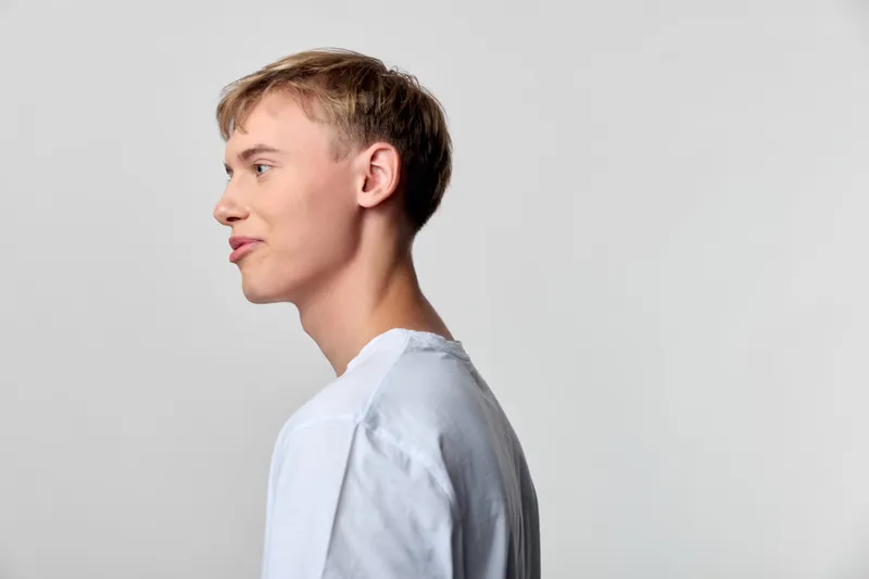 Profile of a man in a white shirt, side view against a neutral studio backdrop, calm expression and clean lighting, minimal composition suitable for business, fashion, or corporate projects