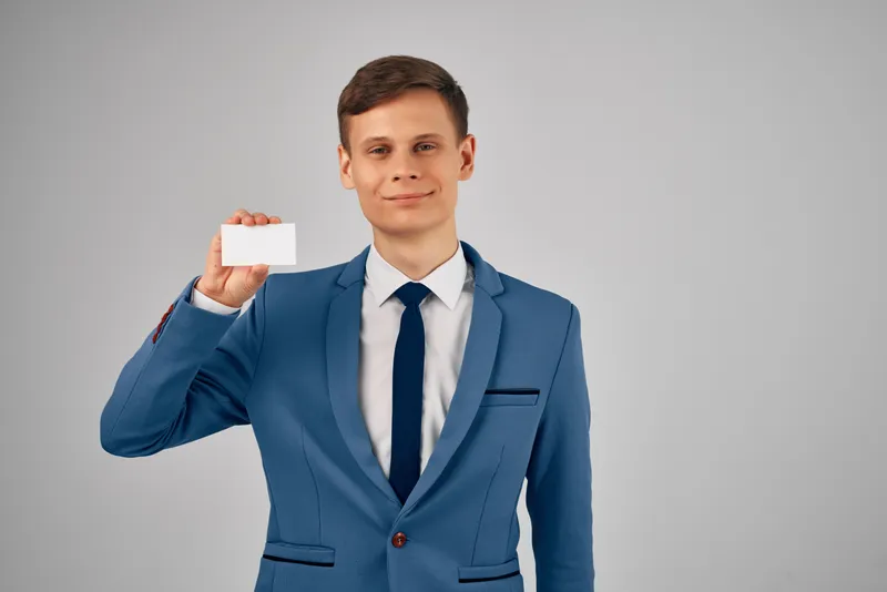 Деловой мужчина в костюме держит визитную карточку, предусмотрено место для копирования для рекламы