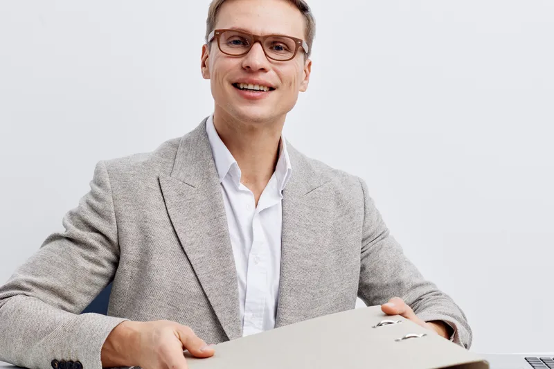 smiling man holding folder wear glasses grey blazer white shirt isolated on white background digital nomad remote work concept