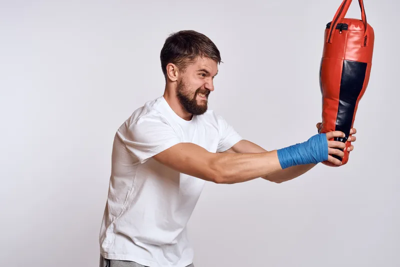 Спортивная машина, боксёрская груша, бинты на руках, упражнение