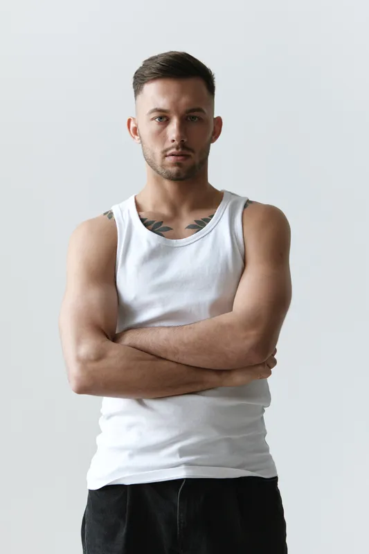 Портрет красивого, серьёзного, загорелого, спортивного, привлекательного мужчины, позирующего на белом студийном фоне