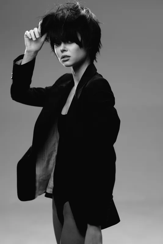 Black and white portrait of a stylish woman with short hair wearing a jacket, showing thoughtful emotion and modern fashion.